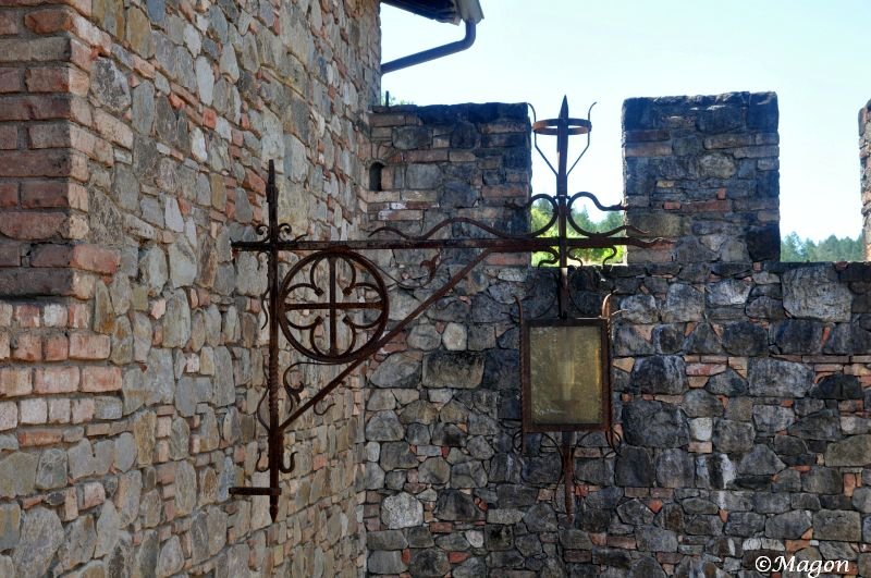 Castello Di Amorosa: кованый фонарь у каменной стены